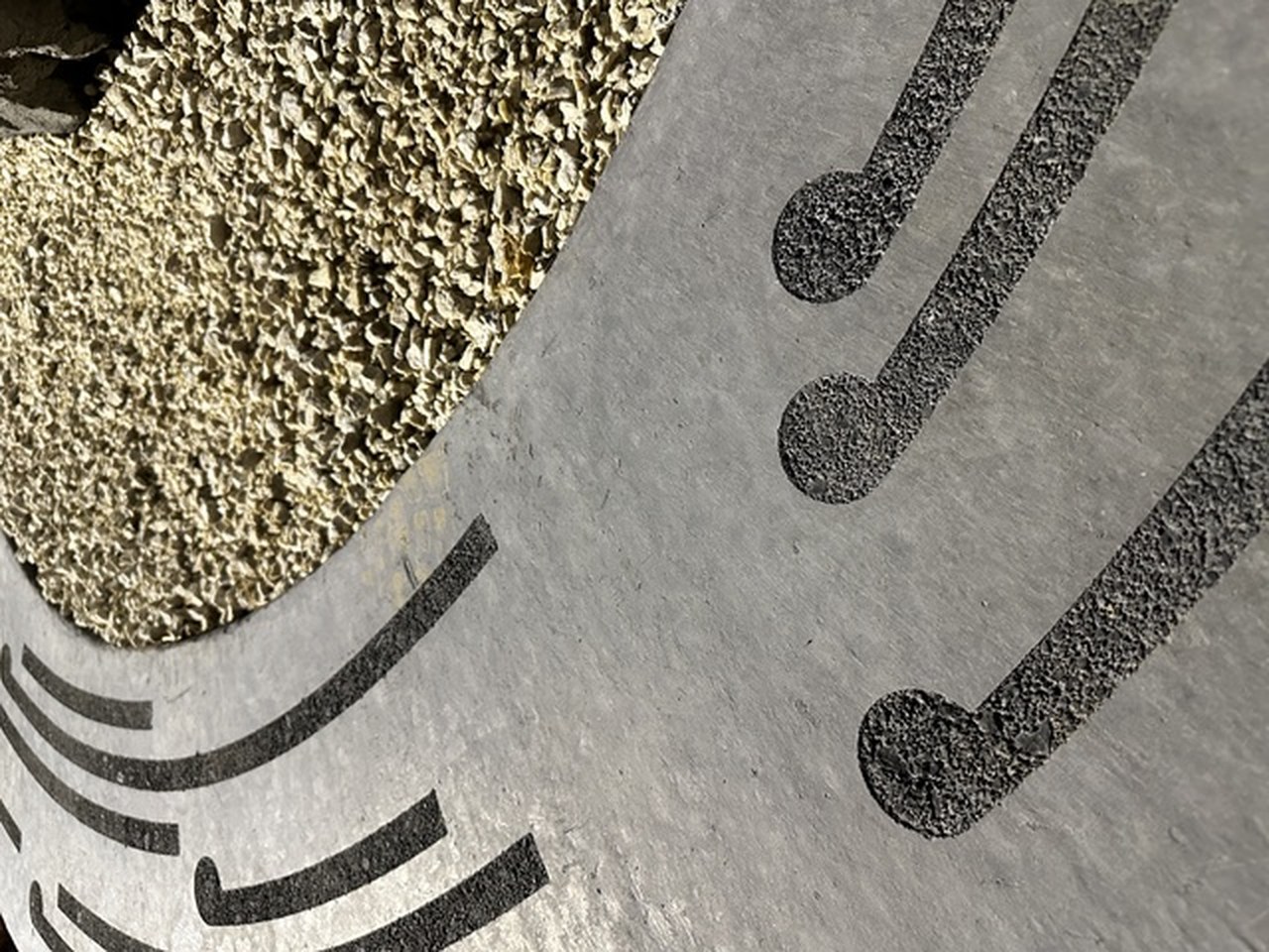 Concrete slab with curved black aggregate inlay lines and exposed gravel, close view