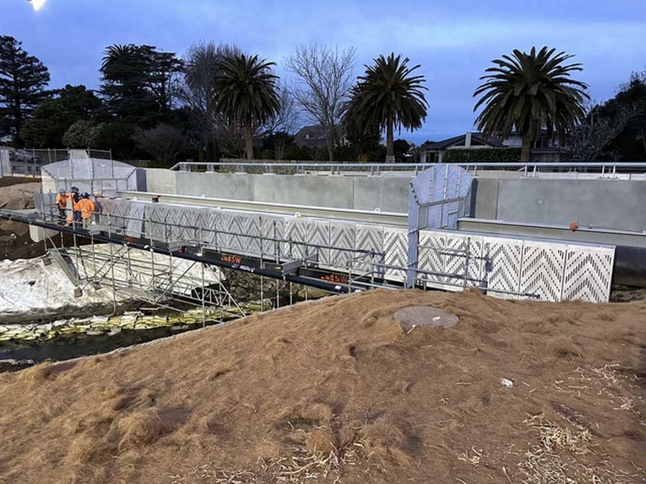 Perforated steel bridge screen under construction with the site crew